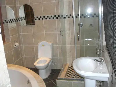 a bathroom with a toilet and a tub and a sink at Boitumelo Guest House in Pretoria
