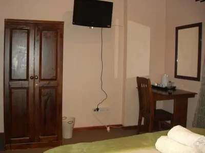 a bedroom with a bed and a desk and a television at Boitumelo Guest House in Pretoria
