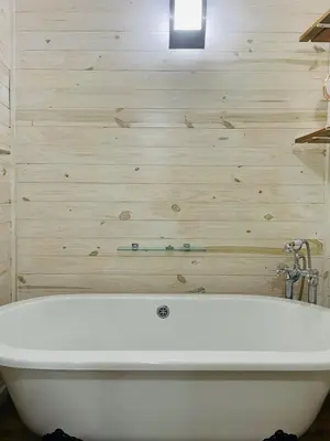 a white bath tub in a bathroom with wooden walls at Eindelik on de Lange in Graskop