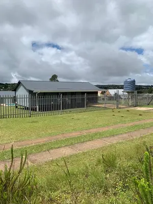 a fence in front of a building in a field at Eindelik on de Lange in Graskop