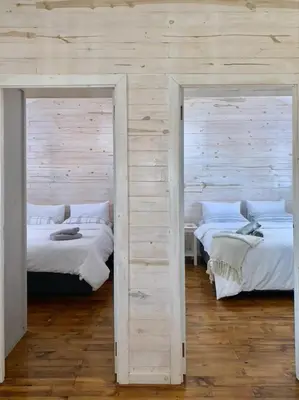 two beds in a room with wooden walls at Eindelik on de Lange in Graskop