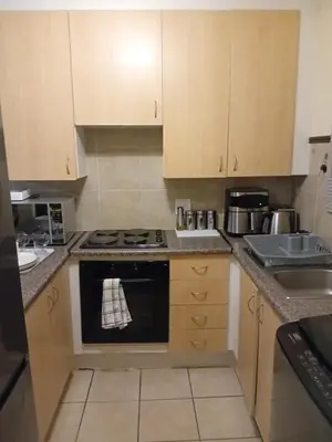 a kitchen with a stove top oven next to a sink at Pretoria North Royal-IN in Akasia