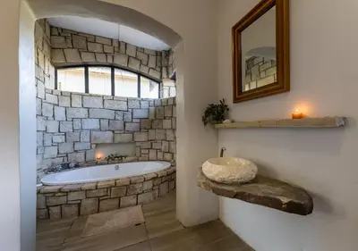 a stone walled bathroom with a tub and a window at Linger at the Lake Chrissiesmeer in Lake Chrissie
