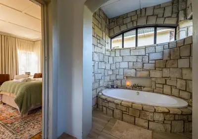 a bathroom with a stone wall and a bath tub at Linger at the Lake Chrissiesmeer in Lake Chrissie