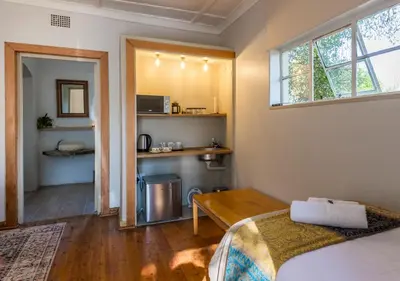 a bedroom with a bed and a table and a window at Linger at the Lake Chrissiesmeer in Lake Chrissie