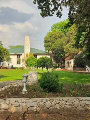 a house with a stone wall in front of a yard at Linger at the Lake Chrissiesmeer in Lake Chrissie