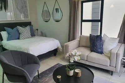 a bedroom with a bed and a couch and a table at Lagoon Aparthotel in Pretoria
