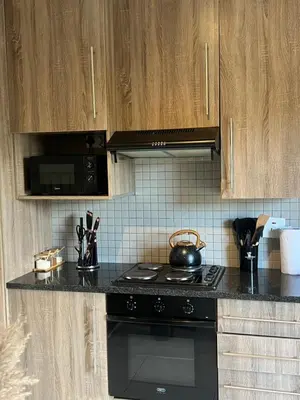 a kitchen with a black stove and wooden cabinets at Hatfield Studio Apartment Units in Pretoria