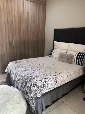 a bedroom with a bed with a black and white comforter at Hatfield Studio Apartment Units in Pretoria