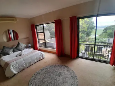 a bedroom with a bed and a large window at 16 Sleeper Holiday Home-Mansion in Hartbeespoort