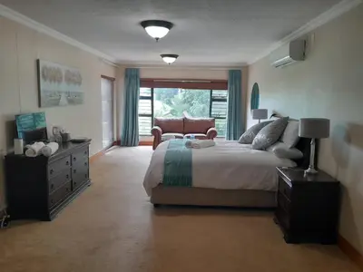 a bedroom with a bed and a chair and a window at 16 Sleeper Holiday Home-Mansion in Hartbeespoort