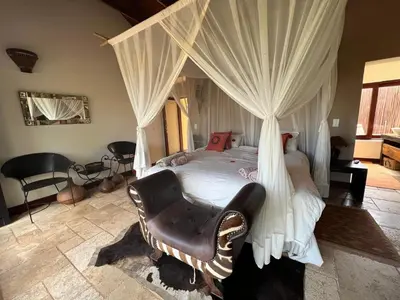 a bedroom with a canopy bed with a chair at Luxury Villa at Elements Golf Course - Bela Bela in Warmbaths