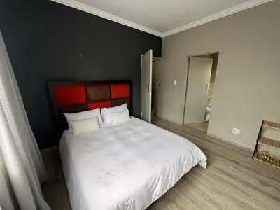 a bedroom with a large white bed with a red headboard at Spacious Midrand 3 Bedroom Near Gallagher, MOA & Gautrain in Midrand