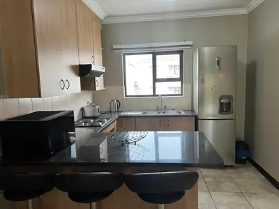 a kitchen with a counter top and a refrigerator at Spacious Midrand 3 Bedroom Near Gallagher, MOA & Gautrain in Midrand