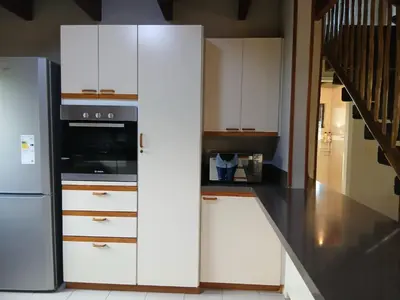 a kitchen with white cabinets and a stainless steel refrigerator at The Swiss Garden in Midrand