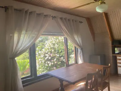 a dining room with a table and a large window at The Swiss Garden in Midrand
