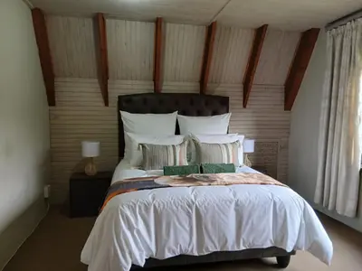 a bedroom with a large bed with white sheets and pillows at The Swiss Garden in Midrand