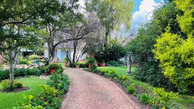 a brick path in a garden with flowers and trees at Midrand Manor Guesthouse in Midrand