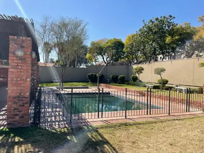 a fence around a swimming pool in a yard at The House of Cataleya in Midrand