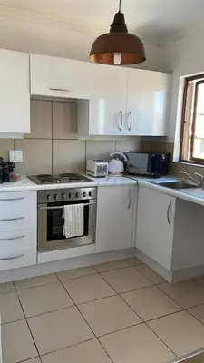a kitchen with white cabinets and a stove top oven at The House of Cataleya in Midrand