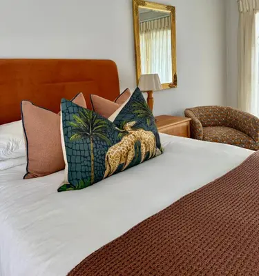 a bedroom with a bed with pillows and a chair at Private African Retreat at 3000ha Mangweni Game Reserve in Elandsbosch
