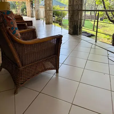 a tiled floor with a wicker chair on a porch at Private African Retreat at 3000ha Mangweni Game Reserve in Elandsbosch