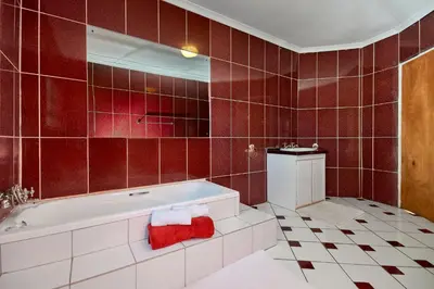 a bathroom with a white tub and red tiles at GlenAustin Garden Haven in Midrand