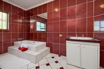 a bathroom with a tub and a sink and red tiles at GlenAustin Garden Haven in Midrand
