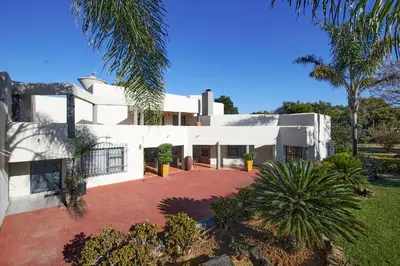 a large white house with palm trees in front of it at GlenAustin Garden Haven in Midrand