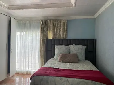 a bedroom with a bed with a large window at XNZN Guest House in Tzaneen
