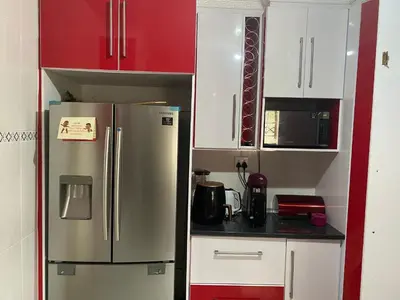 a kitchen with a stainless steel refrigerator and red cabinets at XNZN Guest House in Tzaneen