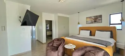 a bedroom with a king sized bed and a chair at Penthouse Menlyn in Pretoria