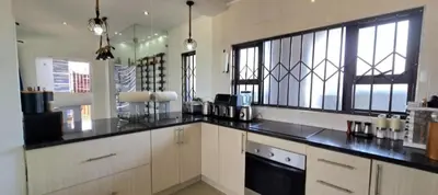 a large kitchen with black counter tops and windows at Penthouse Menlyn in Pretoria