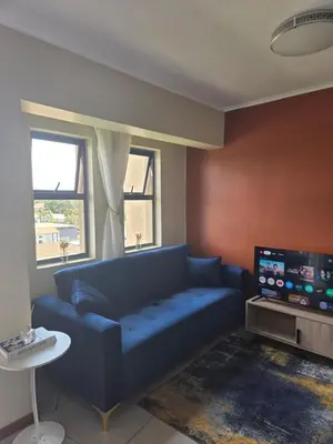 a living room with a blue couch and a tv at Bachelor in Hatfield in Pretoria