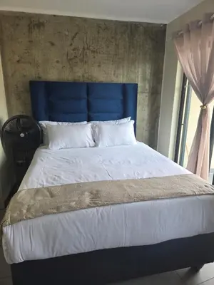 a bed with a blue headboard in a bedroom at Bachelor in Hatfield in Pretoria