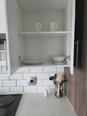 a kitchen cabinet with plates and utensils in it at Bachelor in Hatfield in Pretoria