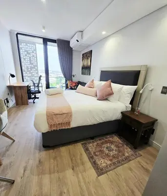 a bedroom with a large bed with pillows and a table at Serenity Escape at Ellipse Waterfall in Midrand
