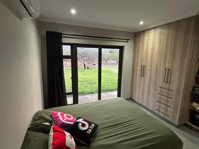 a bedroom with a bed and a large window at House 110 in Hoedspruit