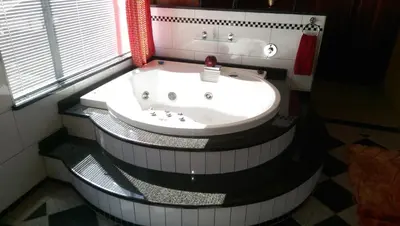 a bath tub in a bathroom with a sink at Red Square Home in Pretoria