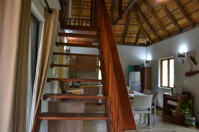 a wooden spiral staircase in a room with a table at Africana Properties Impala Private Villa in Hoedspruit