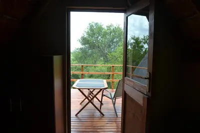 a door leading to a deck with a table and a chair at Africana Properties Impala Private Villa in Hoedspruit