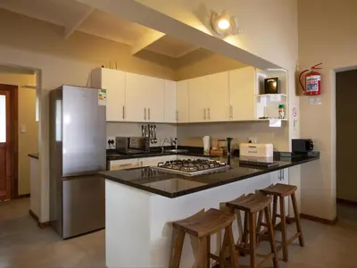 a kitchen with white cabinets and a counter with stools at Africana Properties The Village 25 in Hoedspruit