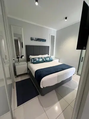 a bedroom with a bed with blue pillows and a television at Mabiyela at Ellipse Waterfall in Midrand