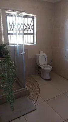 a bathroom with a toilet and a shower with a window at UrbanStay in Pretoria