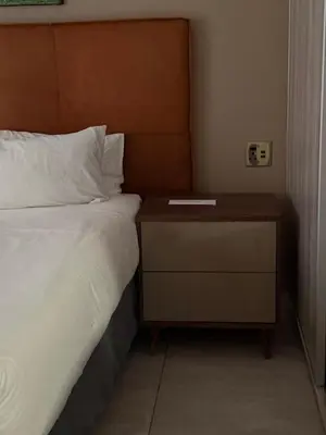 a bed with a nightstand next to a bed with a white bedspread at Dunamis Lodge in Giyani