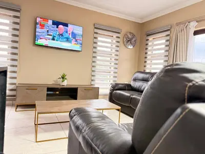 a living room with leather furniture and a flat screen tv at Dunamis Lodge in Giyani