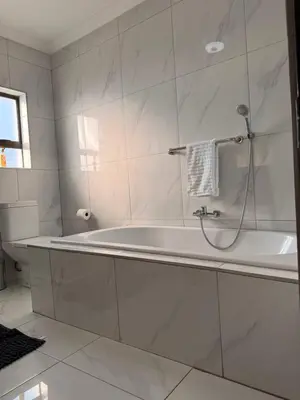 a white bathroom with a tub and a toilet at Dunamis Lodge in Giyani