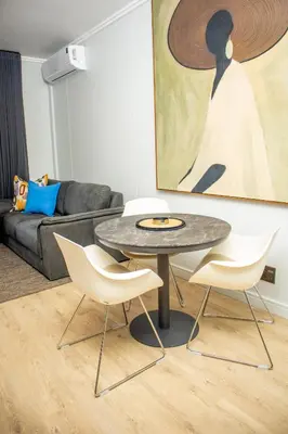 a table and chairs in a living room with a painting at Ellipse Waterfall Premium Apartments - Blue in Johannesburg