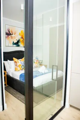 a bedroom with a bed through a glass door at Ellipse Waterfall Premium Apartments - Blue in Johannesburg