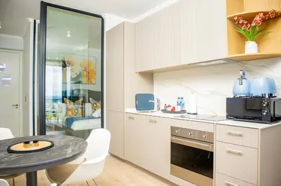 a kitchen with white cabinets and a table at Ellipse Waterfall Premium Apartments - Cream in Johannesburg